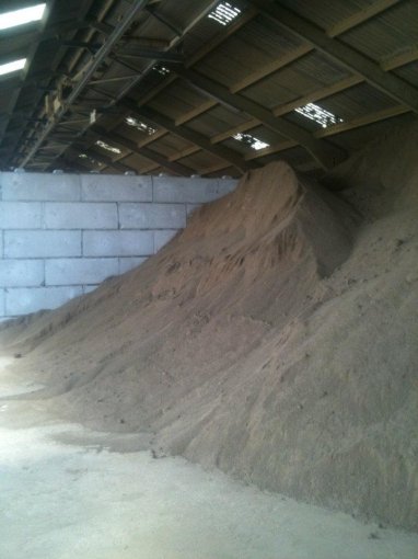 Sand heaped against a Duo block bay wall inside a covered store
