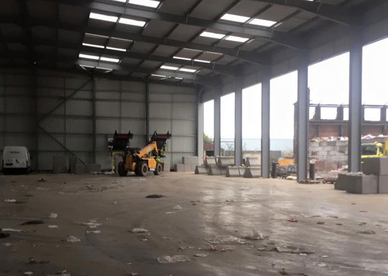 Telehandler working in an open-sided waste facility shed with precast blocks on the floor