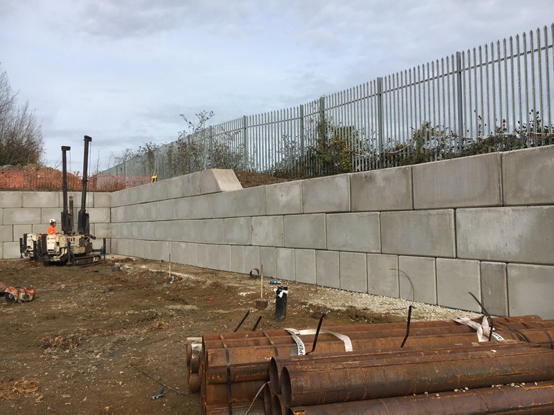 Legato interlocking block wall below palisade fencing on a construction site