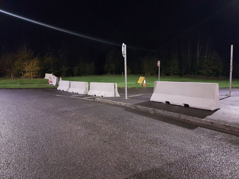 Jersey barriers closing a road at dusk under street lighting