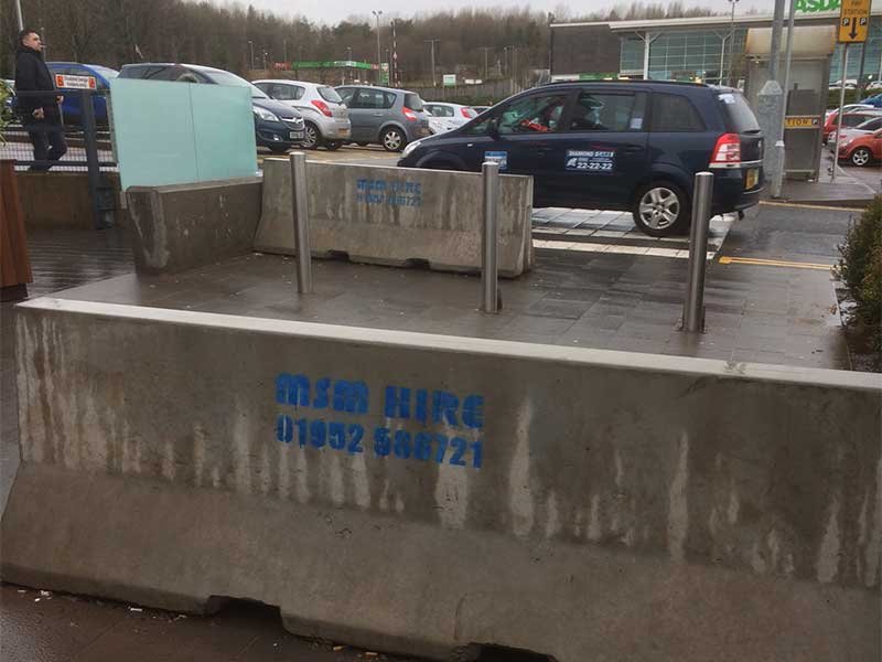 Weathered Jersey barriers dividing a car park from a parking bay