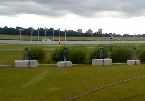 Ballast blocks weighting security fence posts across a grass event field