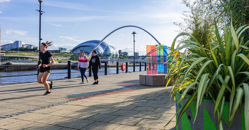 Duo blocks used as quayside seating and planters as people walk past