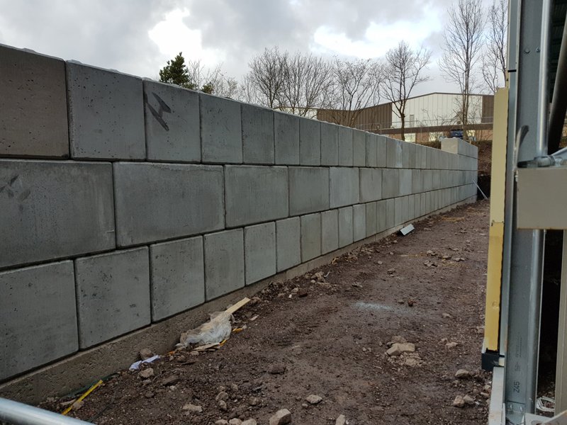 Long Legato block wall running along the edge of an industrial site