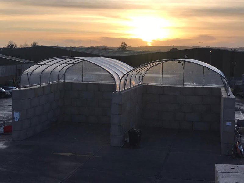 Arched shelters on Legato block walls silhouetted against a sunset