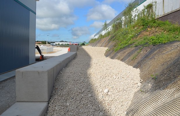 Stepped Legato block retaining wall running alongside a gravel drainage channel
