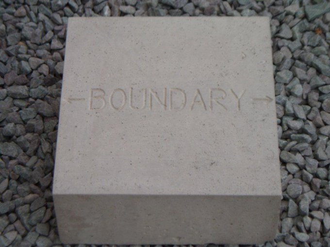 Concrete marker block cast with the word Boundary, bedded in gravel