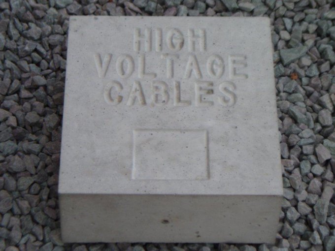 Cable marker block cast with High Voltage Cables lettering, bedded in gravel