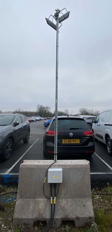 Concrete barrier block ballasting a mobile lighting mast in a car park