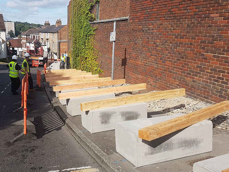 Duo blocks with timber rails being installed as no-dig fencing along a street