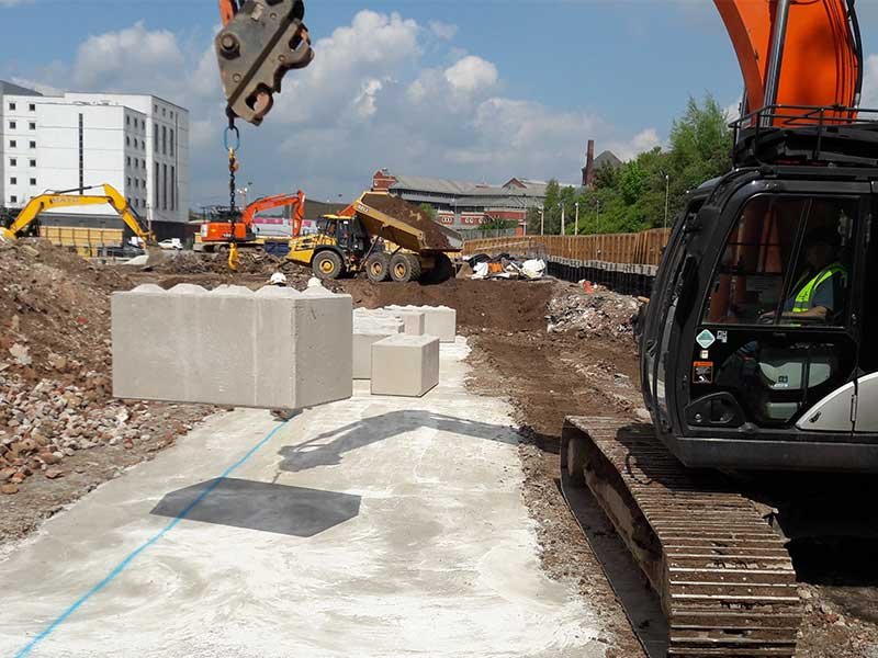 Excavator offloading Legato blocks onto a cleared urban construction site