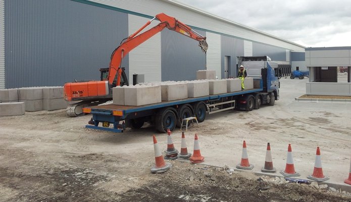 Excavator lifting Legato blocks from a delivery lorry outside a new industrial unit