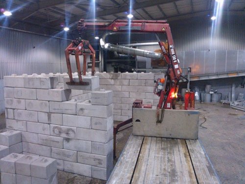 Lorry crane placing Duo blocks to build storage bay walls indoors