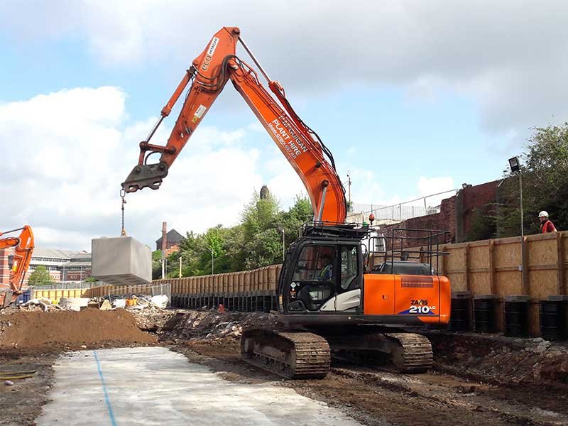 Tracked excavator working on a cleared site beside sheet piling