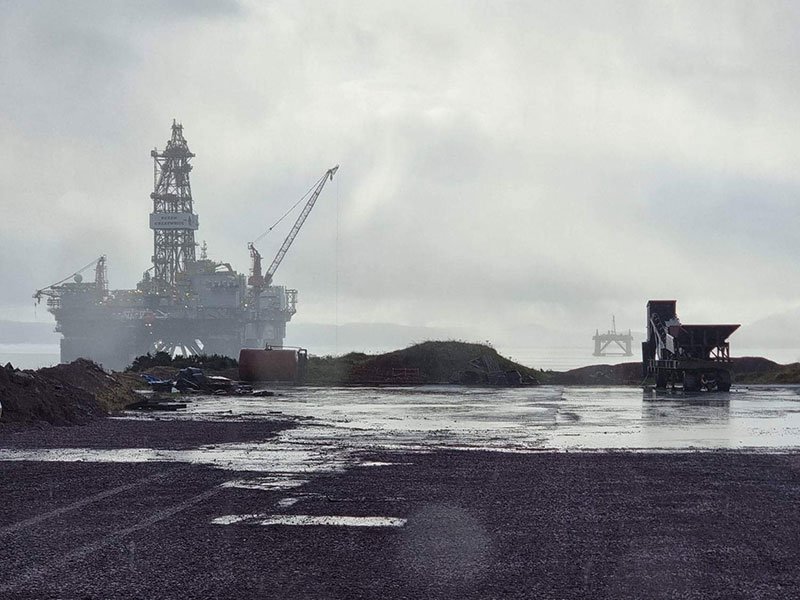 Offshore rig moored in mist beyond a wet decommissioning yard