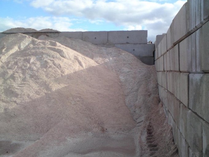 Interlocking block walls retaining a heaped stockpile of road salt outdoors