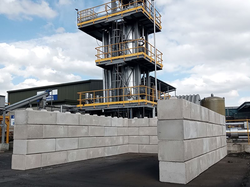 Duo block storage bays in front of a tall industrial processing plant