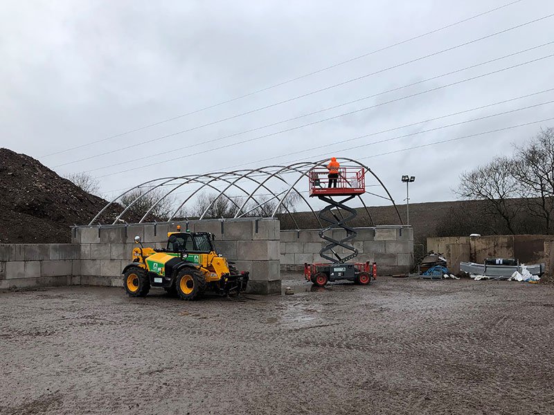 Telehandler and scissor lift building a canopy store on interlocking block walls