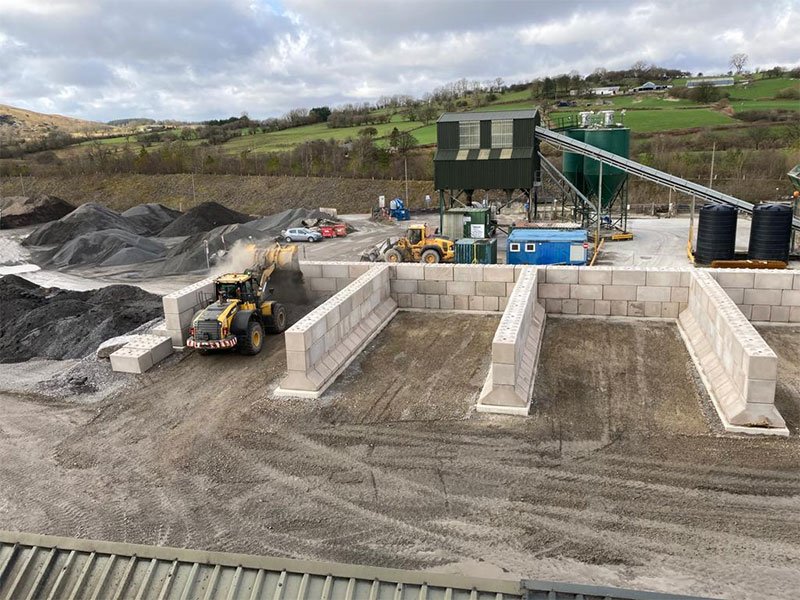 Interlocking block storage bays holding aggregate stockpiles at a quarry, loading shovel working