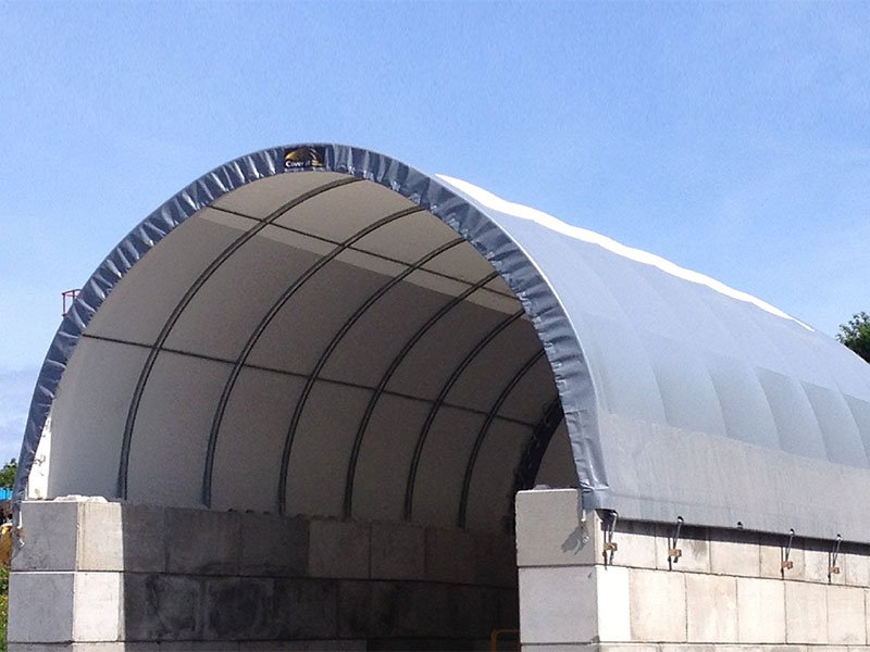 Fabric-covered storage building springing from Legato interlocking block walls