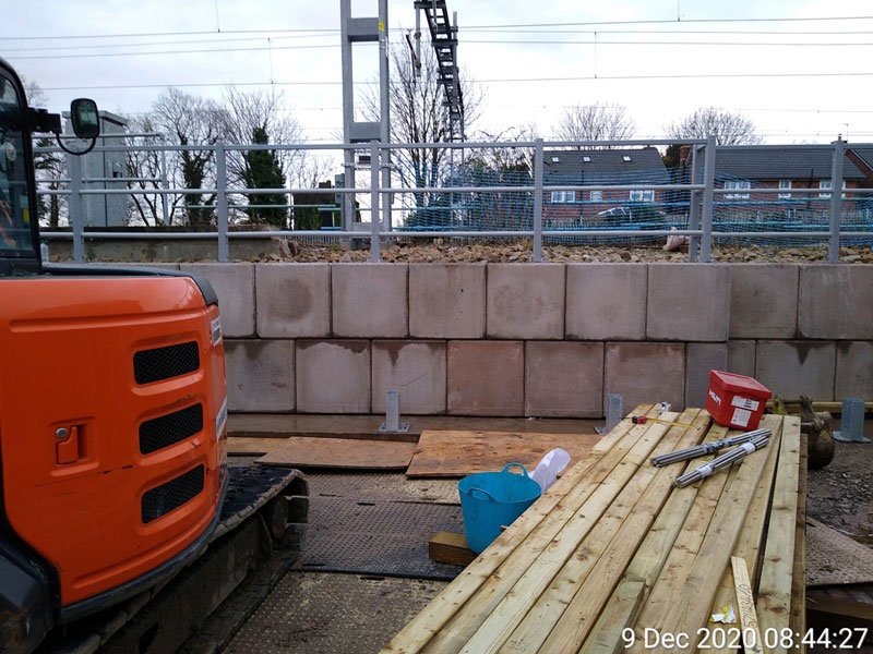 Legato interlocking blocks forming a safety wall beside a railway with an excavator working