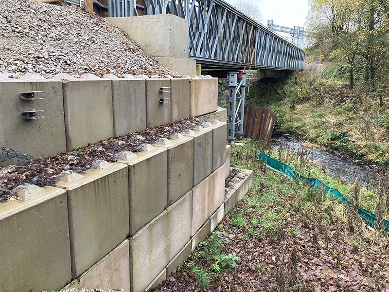 Legato blocks forming abutment walls beneath a steel bridge