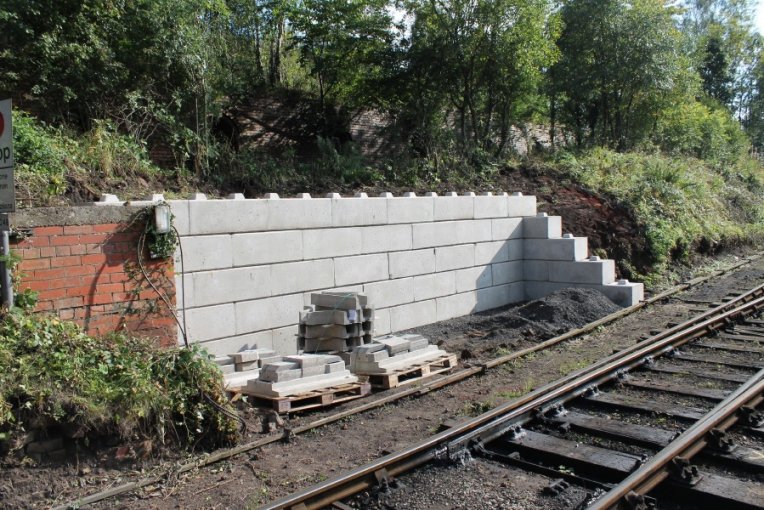 Stepped interlocking block retaining wall along a wooded railway embankment