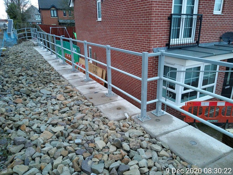 Interlocking block retaining wall and handrail running behind new brick houses