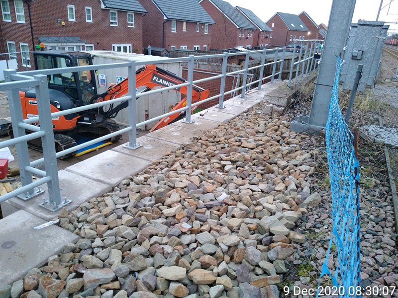 Excavator working beside a block embankment retaining wall on a housing development