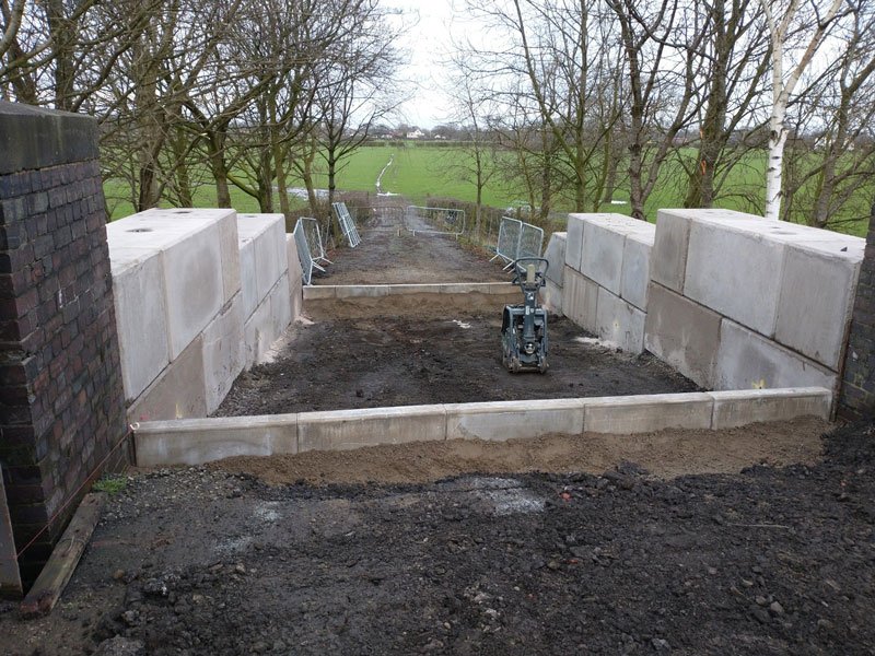 Interlocking block walls flanking a graded access beside a brick wall