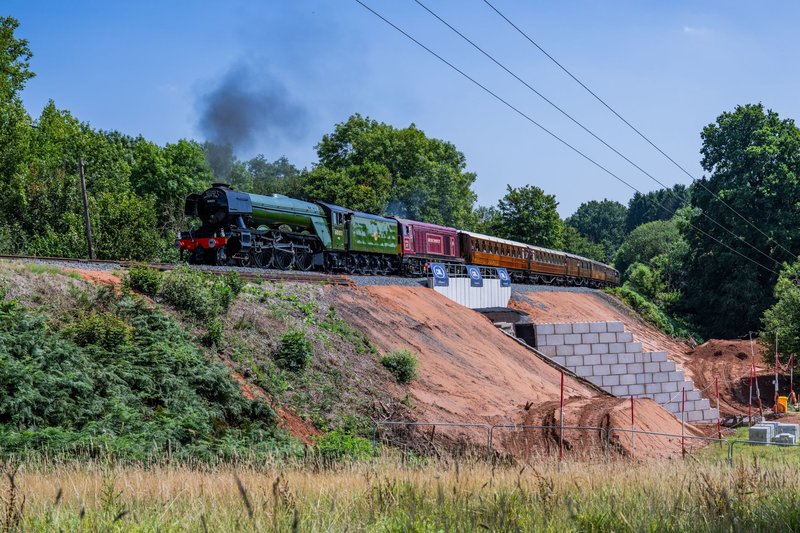 Steam locomotive crossing an embankment supported by a Legato block retaining wall