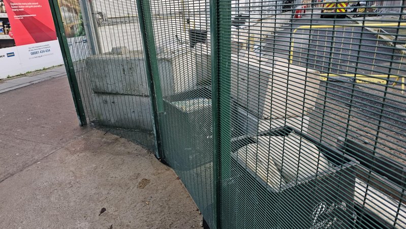 Green mesh hoarding panels ballasted by concrete blocks on a city pavement