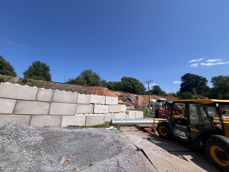 Legato retaining wall holding back an embankment with a telehandler working nearby