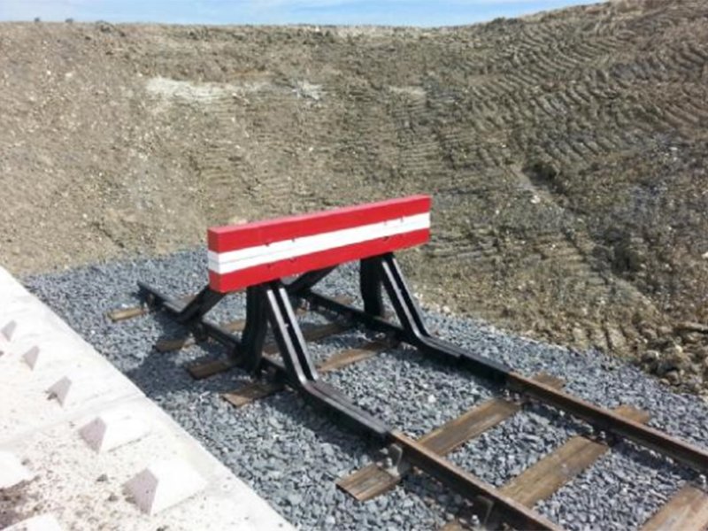 Railway buffer stop on track beside a Legato block loading platform wall