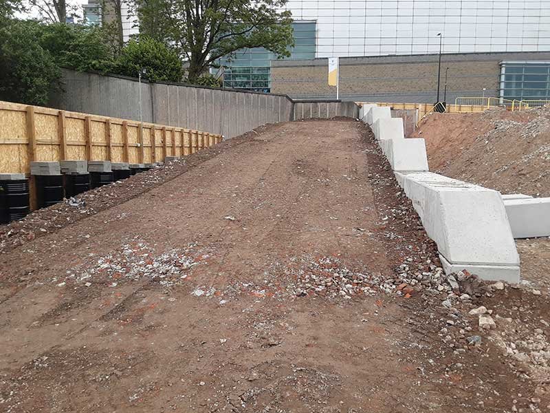 Earth ramp rising between interlocking block retaining walls at a city site