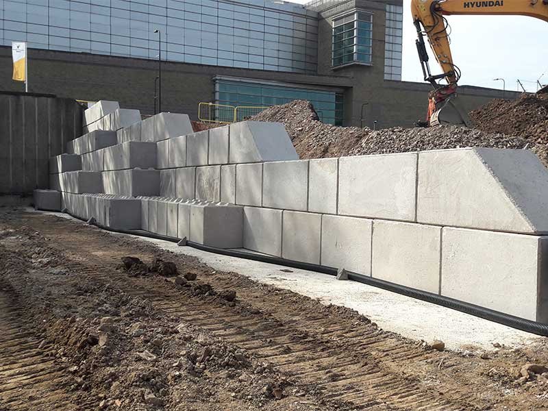 Stepped interlocking block retaining wall backfilled alongside a building