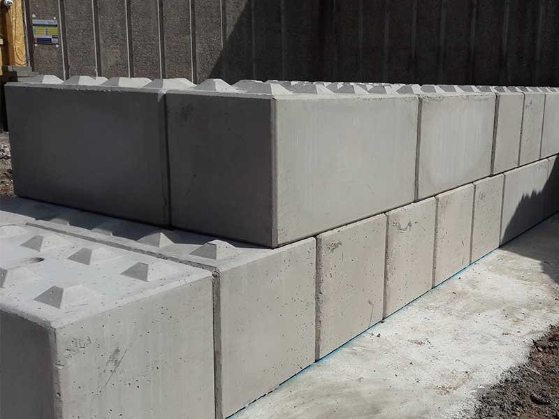 Two courses of Legato interlocking blocks set against a ribbed concrete wall