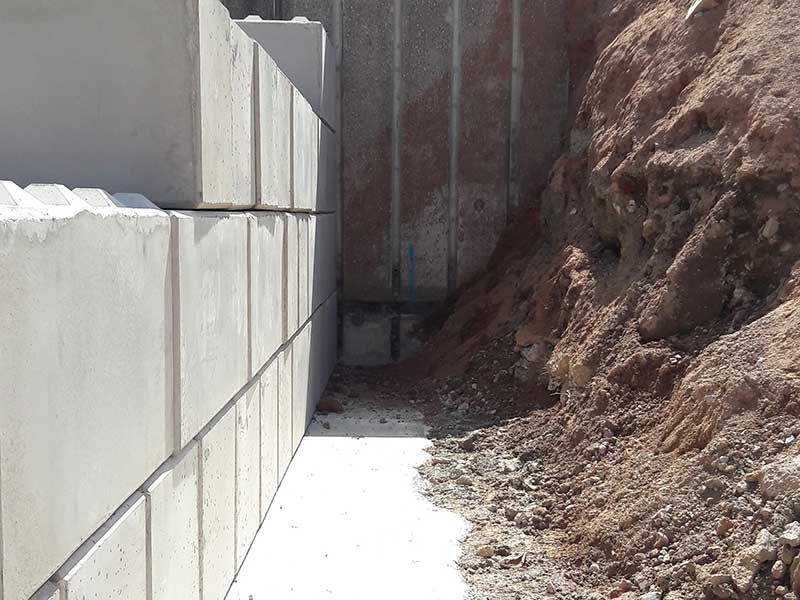 Interlocking block wall retaining a steep bank of excavated earth