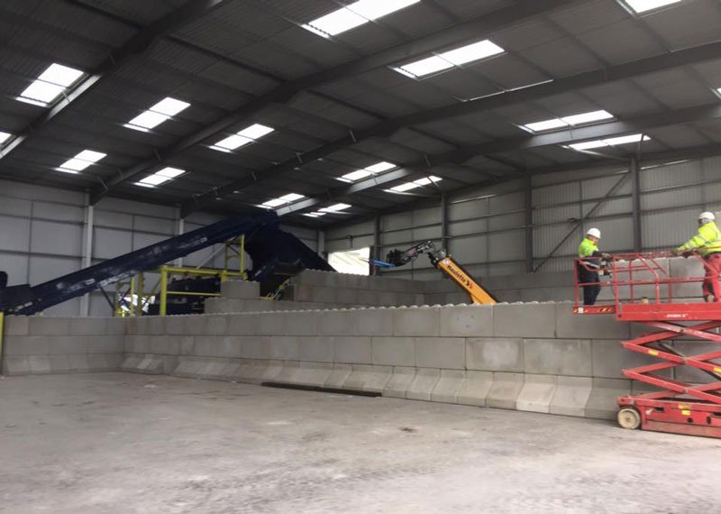 Part-built Legato interlocking block wall with workers on a scissor lift inside a shed