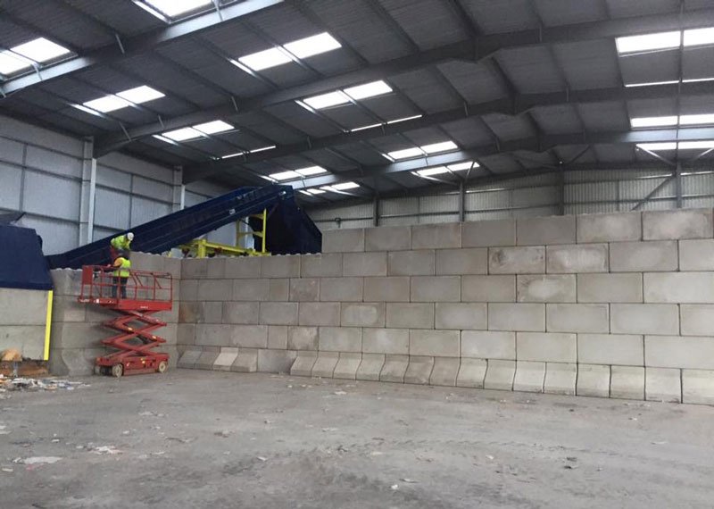 Completed Legato interlocking block wall lining a recycling shed with a conveyor above