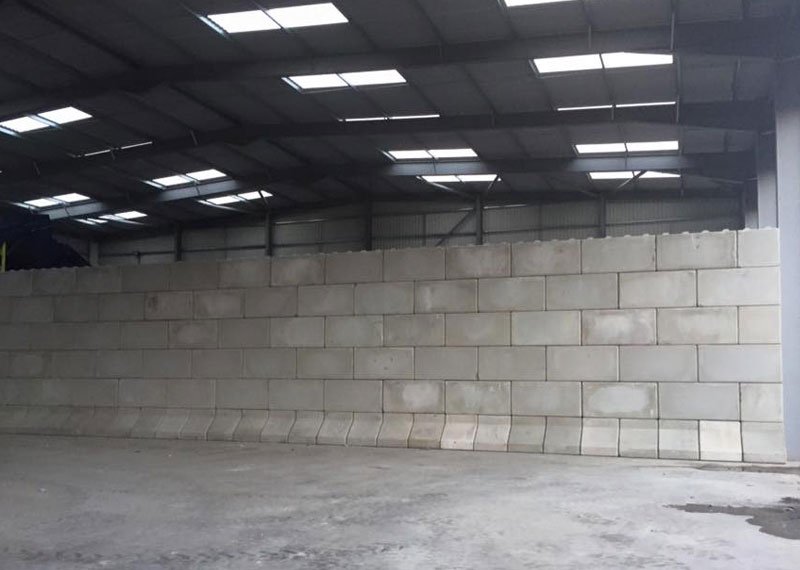 Long interlocking block wall lining an empty warehouse bay