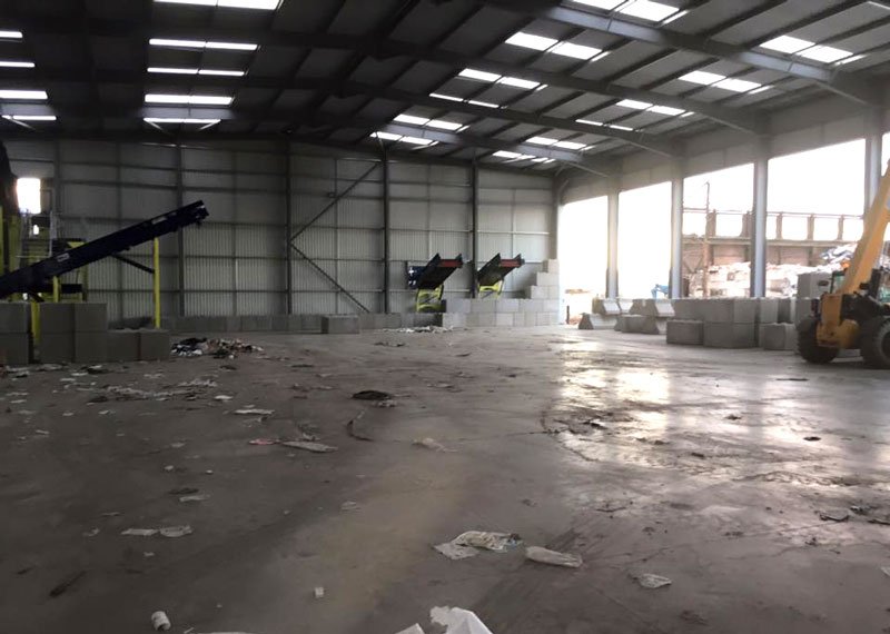 Waste unit interior with conveyors and interlocking blocks stacked by the door