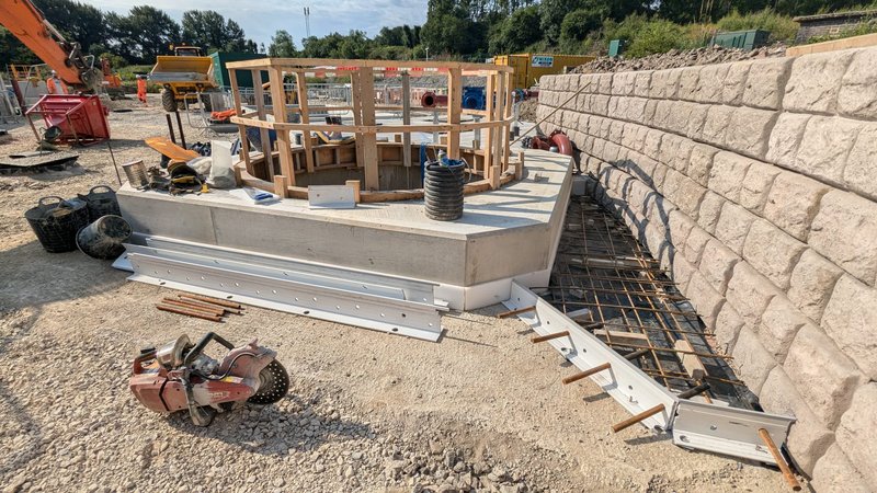 Cobblestone-finish Retainer-Rock wall under construction beside timber formwork and site tools