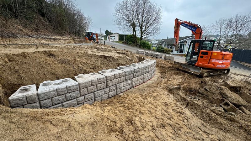 Curved cobblestone-finish Retainer-Rock wall built by an excavator on a lodge site