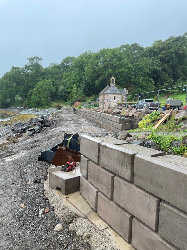Smooth-faced Retainer-Rock retaining wall being built on a rocky shoreline