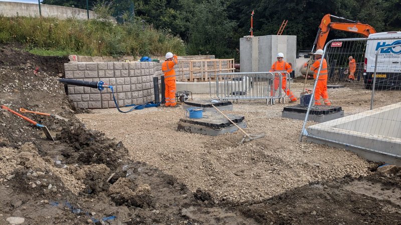 Workers installing Retainer-Rock walling units on a muddy construction site