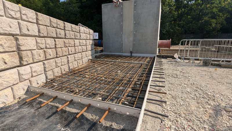 Retainer-Rock wall with cobblestone finish beside a reinforced slab awaiting concrete