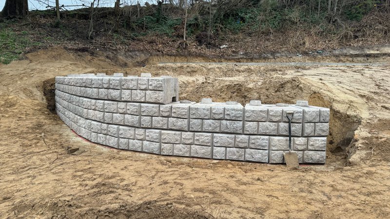 Curved cobblestone faced Retainer-Rock walling built into a sandy bank