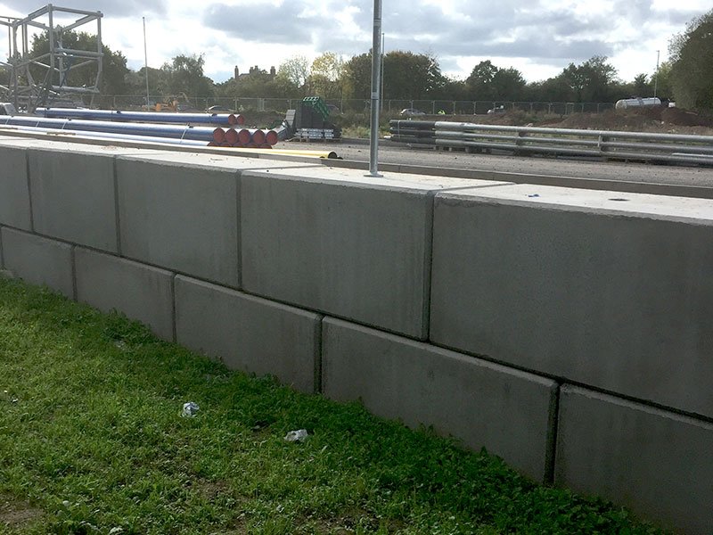 Low interlocking block retaining wall edging a yard beside a grass verge