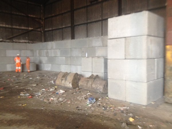 Legato block dividing wall inside a warehouse with operatives in the background